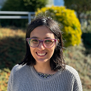 Inés, adulta joven con cabello lacio oscuro hasta los hombros, gafas de ver y gran sonrisa