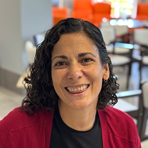 Iria, mujer joven adulta, con cabello rizado corto y expresión sonriente