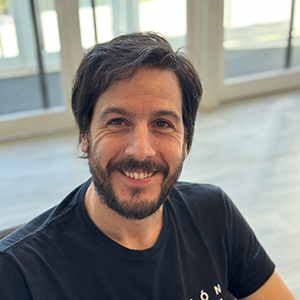Juan Luis, hombre joven adulto con cabello corto, sonriendo y postura profesional