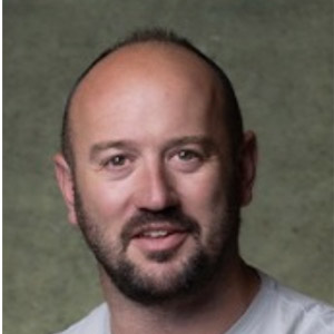 Levi, joven adulto con barba sonriendo amablemente mientras mira a la cámara