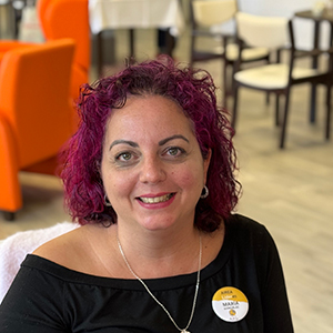 María, mujer adulta con cabello rojo ondulado suelto hasta los hombros, sonriendo con mirada amable