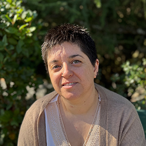 Vanesa, mujer adulta con cabello corto y oscuro, sonriendo levemente, con un parque de fondo