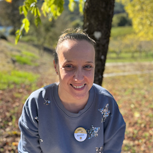 Agueda, mujer de mediana edad con el pelo castaño recogido, sonriendo a la cámara